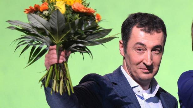 Ein Mann im Anzug hält einen bunten Blumenstrauß in der Hand.