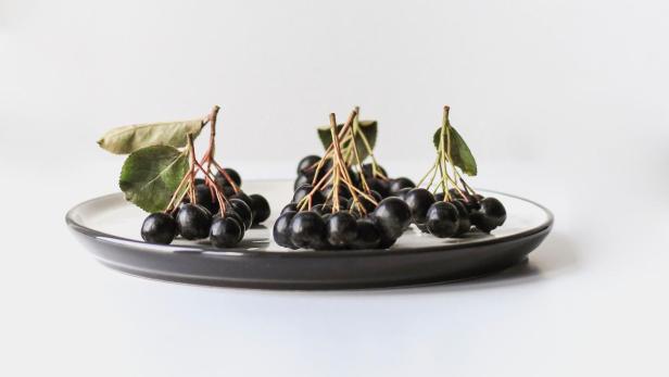 Aroniabeeren liegen auf einem Teller.