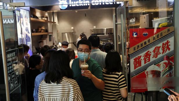 Die Leute stehen Schlange bei Luckin Coffee in Peking. 