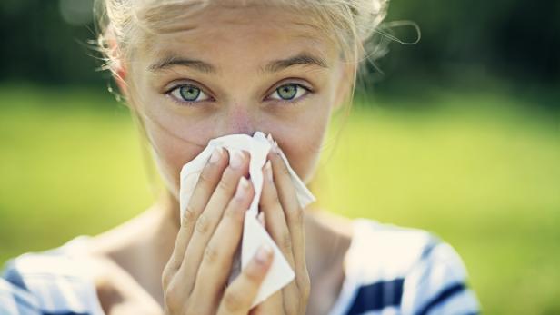 Teenage girl with allergy blowing nose