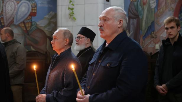 Wladimir Putin und Alexander Lukaschenko mit Kerzen in einer Kirche.