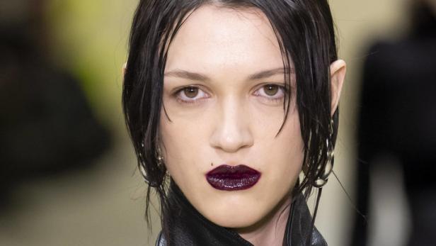 Eine Frau mit dunklem Lippenstift und einem schwarzen Lederjackett.