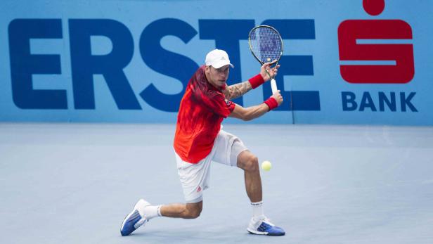 Ein Tennisspieler schlägt einen Ball vor dem Hintergrund einer „Erste Bank“-Werbung.