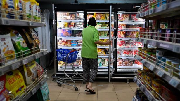 Eine Frau öffnet einen Gefrierschrank in einem Supermarkt in China.