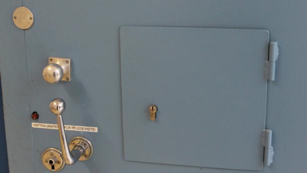 Detailaufnahme einer blauen Metalltür mit verschiedenen Schlössern und einem Hebel.