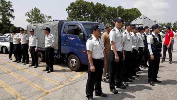 Eine Reihe südkoreanischer Polizisten steht vor einem blauen Lastwagen.