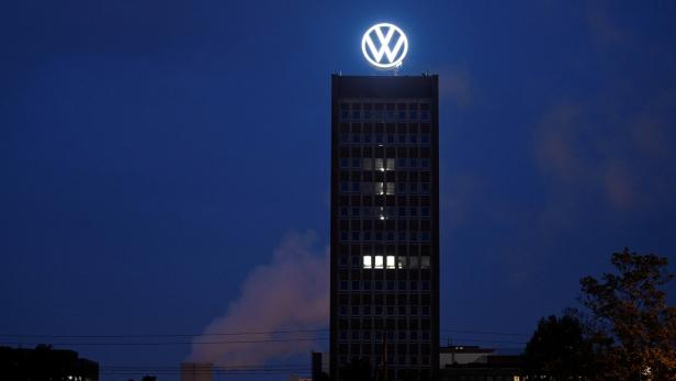 Das Volkswagen-Logo leuchtet auf der Spitze eines hohen Bürogebäudes bei Nacht.