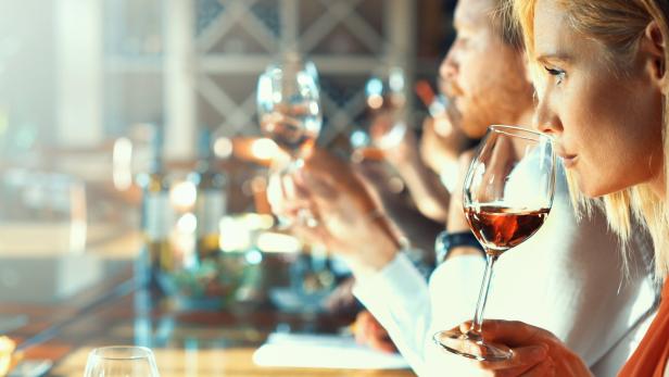 Frau riecht an einem Glas Rotwein.