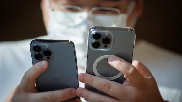 Ein Mann vergleicht in einem Apple-Store in China zwei iPhone-Modelle.