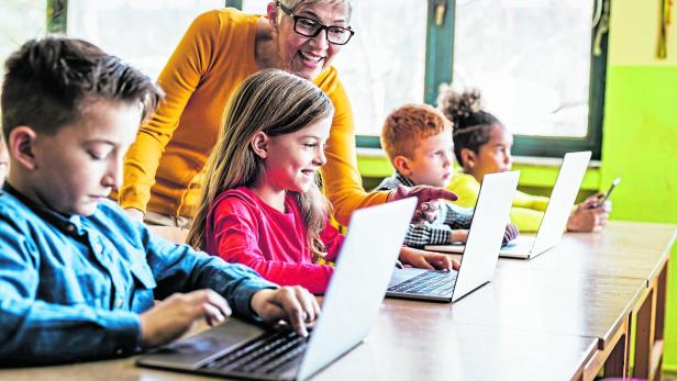 Happy mature teacher assisting her students on computer class at school. Happy mature teacher assisting her students on computer class at school.