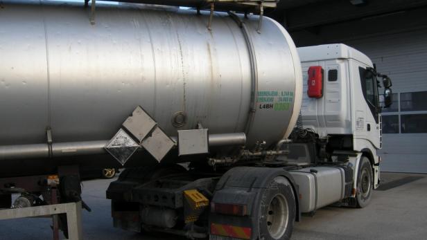 Ein Tanklastwagen mit Gefahrgutkennzeichnung steht auf einem Parkplatz.