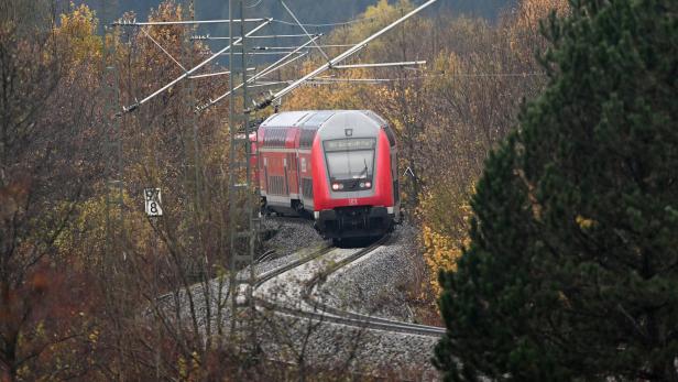 Ein roter Doppelstockzug der Deutschen Bahn fährt durch eine herbstliche Landschaft.