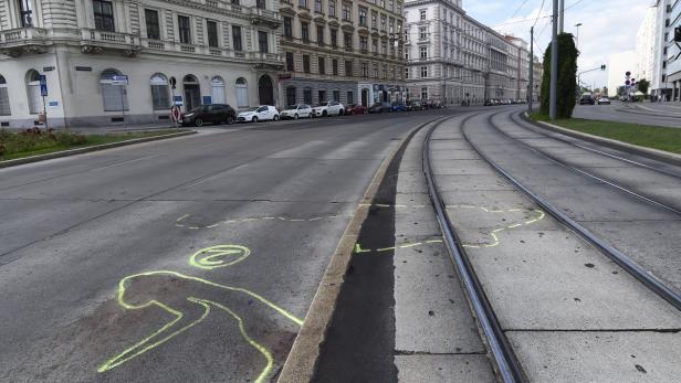 Auf einer Straße in Wien sind Umrisse einer Person und Markierungen aufgemalt.