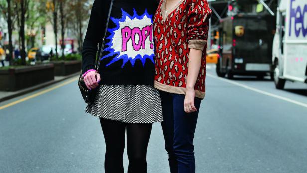 Zwei junge Frauen stehen auf einer Straße in der Stadt.