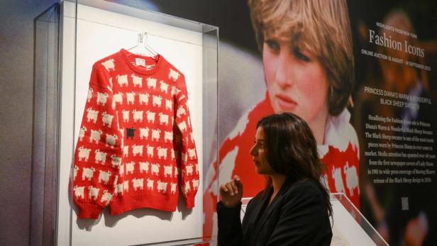 Eine Frau betrachtet Prinzessin Dianas „Black Sheep“-Pullover in einer Ausstellung.