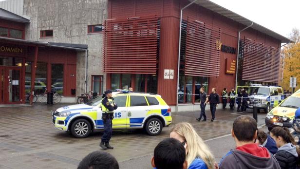 Polizisten und Menschen stehen vor dem Gebäude der Kronan Schule in Trollhättan.