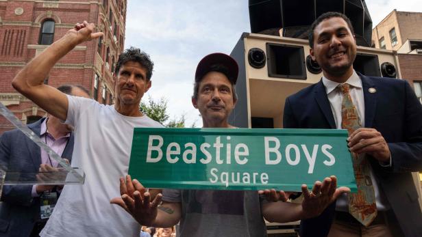 Die beiden Bandmitglieder Adam "Ad-Rock" Horovitz und Michael "Mike D" Diamond und Stadtratsmitglied Christopher Marte halten das Straßenschild für den "Beastie Boys Square" in die Höhe. 