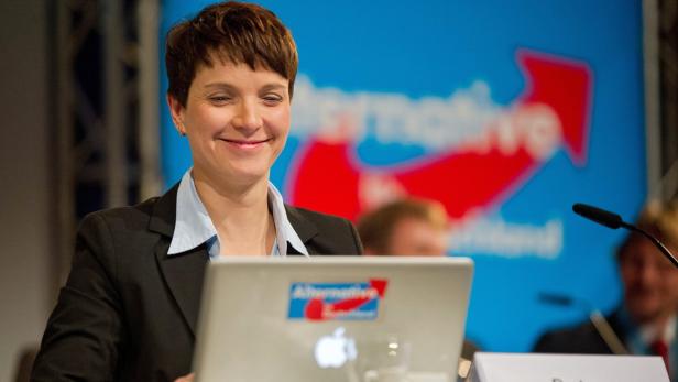 Eine Frau lächelt vor einem Laptop mit dem Logo der „Alternative für Deutschland“.