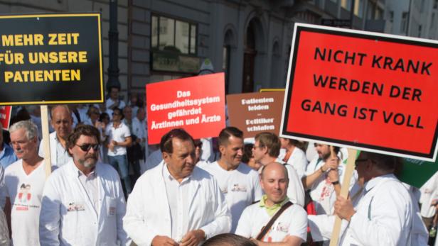 Ärzte und Unterstützer demonstrieren mit Schildern für mehr Zeit für Patienten und gegen den Notstand im Gesundheitswesen.