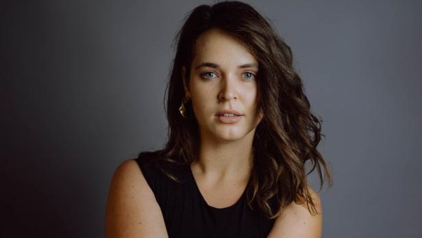 Eine Frau mit Sternenmuster-Strumpfhose sitzt vor einem grauen Hintergrund.