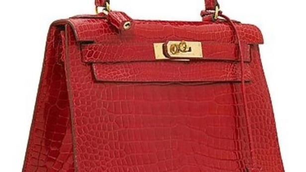 Eine rote Handtasche mit Krokodilmuster und goldenen Akzenten.