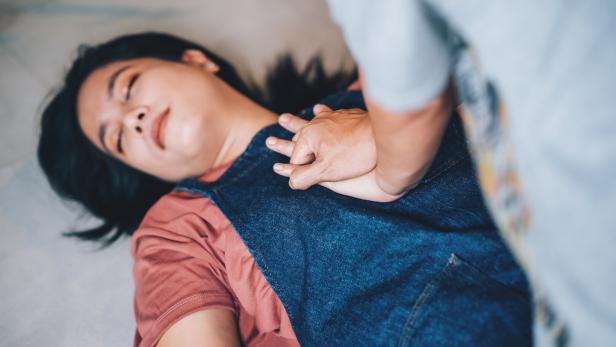 Eine Person reanimiert eine weibliche Person am Boden.