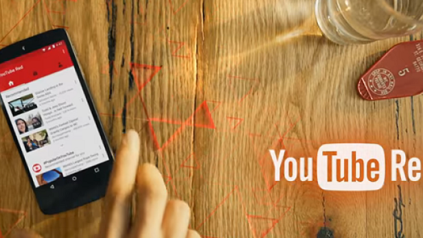 Ein Smartphone mit der YouTube Red App liegt auf einem Holztisch.