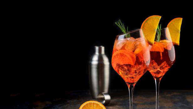 Zwei Gläser Aperol Spritz mit Orangenscheiben und Eiswürfeln.