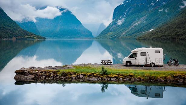 Wohnmobil vor Panorama mit einem See und Bergen.