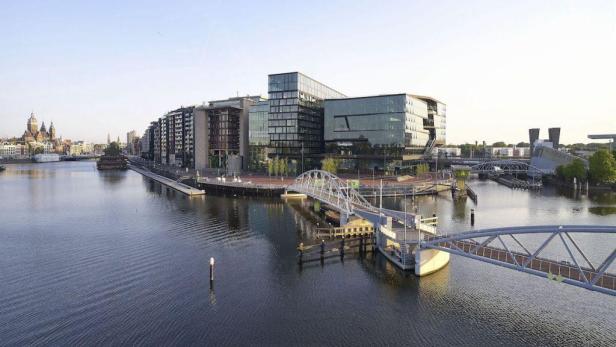 Der Booking.com Campus in Amsterdam mit einer Brücke über das Wasser.