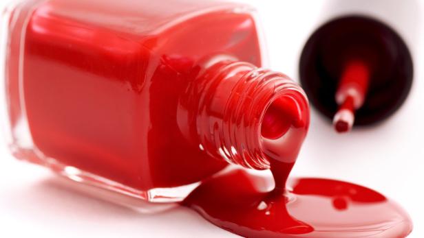 Aus einer umgekippten Flasche läuft roter Nagellack.