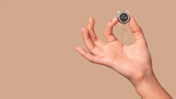 Der Gehirnchip von Neuralink wird von einer Hand gehalten. 