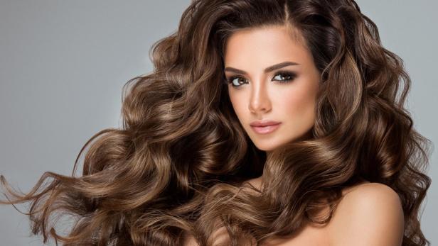 Eine Frau mit langen, gewellten braunen Haaren.