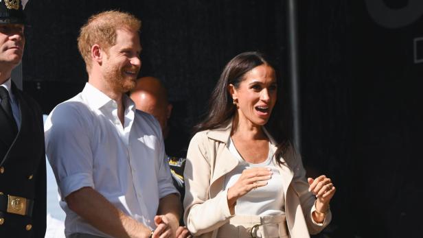 Meghan Markle und Prinz Harry stehen zusammen auf einer Bühne.