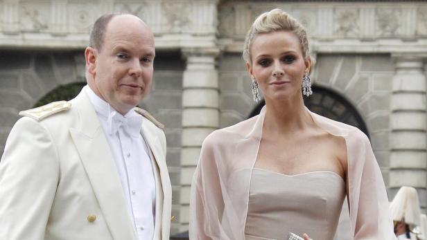 Fürst Albert II. von Monaco und seine Frau Charlène stehen vor einem Gebäude.