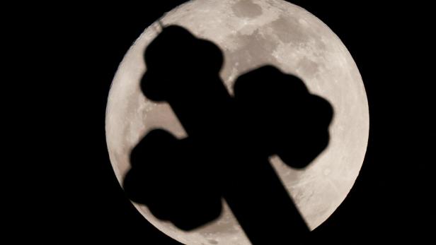 The cross of St. Antony Church is seen as a full moon known as the "Buck Moon" rises over the capital city of Cairo