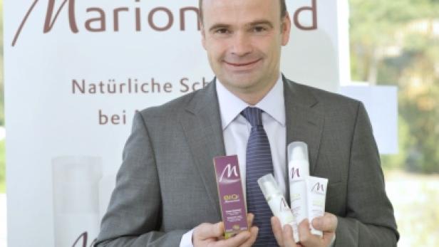 Ein Mann im Anzug präsentiert Hautpflegeprodukte der Marke Marionnaud.