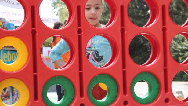 Ein Mädchen schaut durch die Löcher eines roten Spielzeugs.