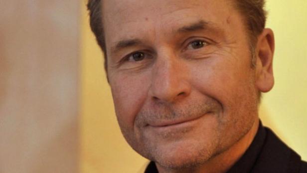 Porträt eines lächelnden Mannes vor einem gelben Hintergrund.