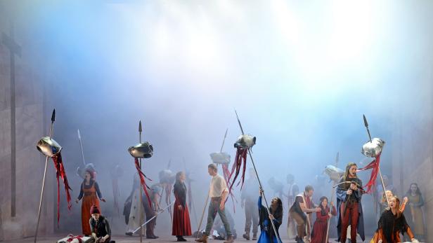 Eine Theaterszene mit Schauspielern in mittelalterlichen Kostümen und Speeren mit Helmen.