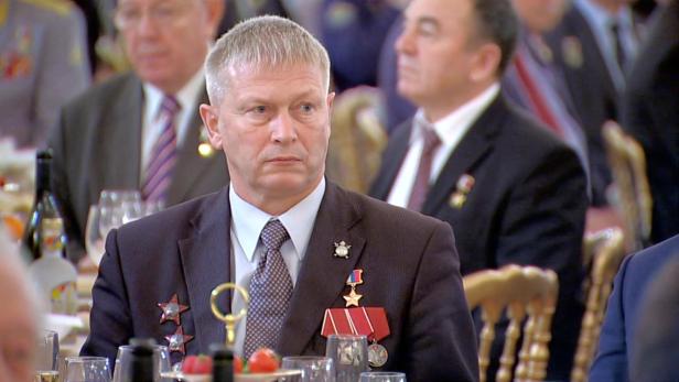 Andrei Troschew sitzt, ausgestattet mit vielen Ordnen, bei einem feierlichen Anlass am Tisch