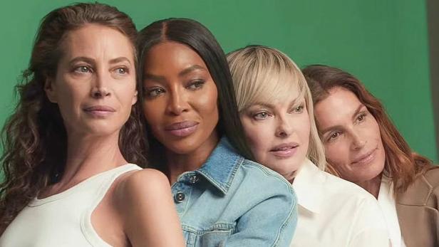 Vier Frauen posieren vor einem grünen Hintergrund.