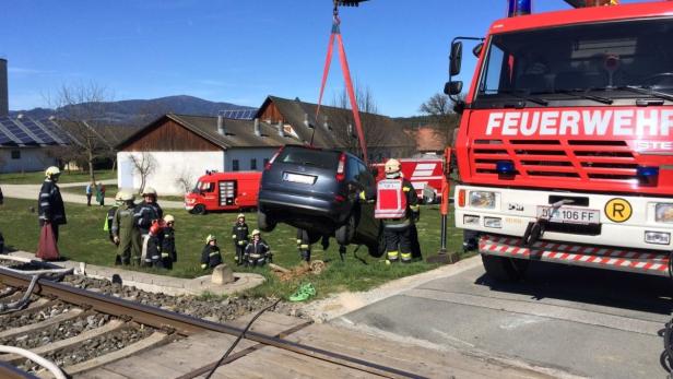 Ein Auto wird von der Feuerwehr von einem Bahnübergang gehoben.