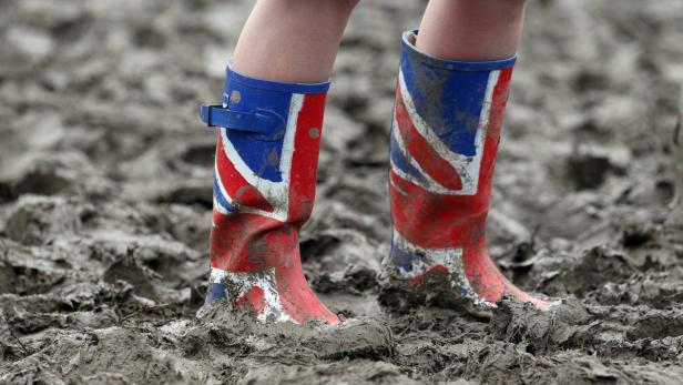 Ein Paar Gummistiefel mit dem Union Jack-Motiv stehen im Schlamm.