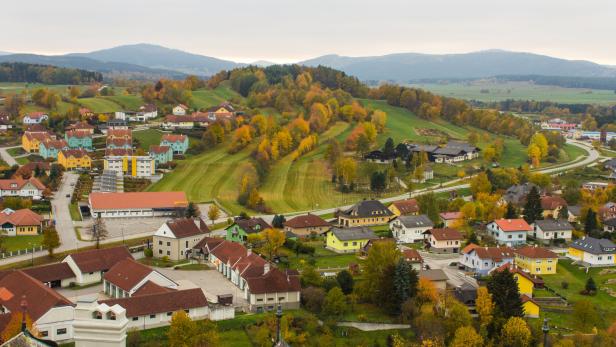Ein Blick auf eine ländliche Gemeinde mit bunten Häusern und herbstlichen Bäumen.