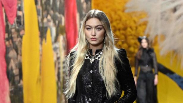 Gigi Hadid läuft in einem glitzernden schwarzen Hosenanzug über einen Laufsteg.
