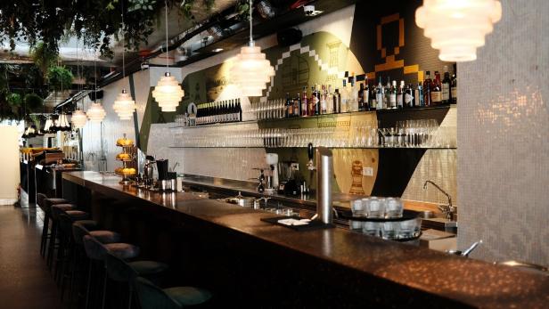 Eine Bar mit Hockern, Getränken und dekorativen Lampen.