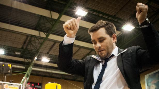Ein Mann im Anzug jubelt auf einem Basketballfeld.