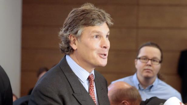 Ein Mann im Anzug spricht vor einer Gruppe von Menschen.