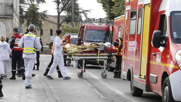 Rettungskräfte schieben eine Person auf einer Trage zu einem Krankenwagen.